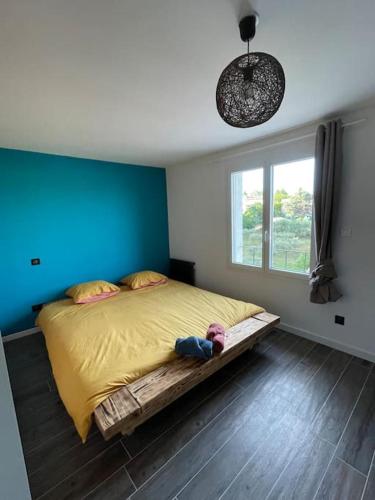 Cet appartement comprend une chambre dotée d'un lit avec un mur bleu et une fenêtre. dans l'établissement Maison de village avec terrasse, à Valensole