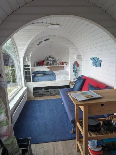 a small room with a bed and a table at Dreckly cabin - Lydcott Glamping with Cornish sea views in Looe