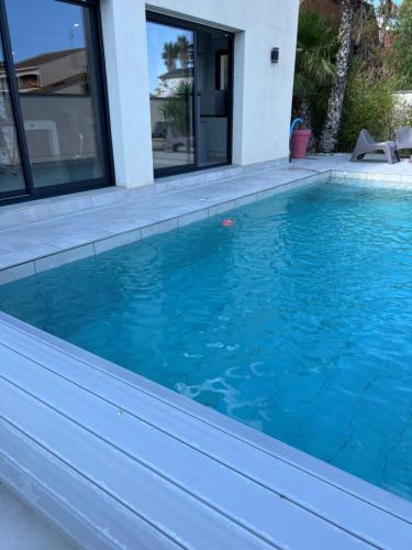 une piscine avec de l'eau bleue devant une maison dans l'établissement villa Wamal, à Mauguio