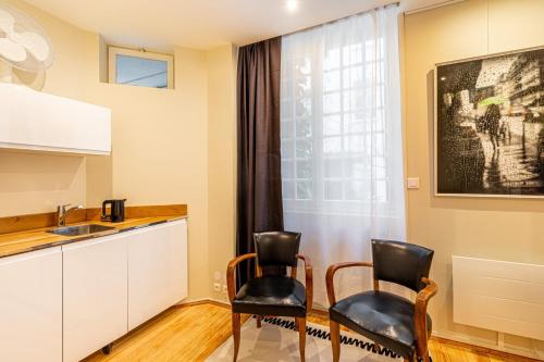 - une cuisine avec 2 chaises, une table et un évier dans l'établissement GuestReady -Beautiful 2-Room in the Heart of Paris, à Paris