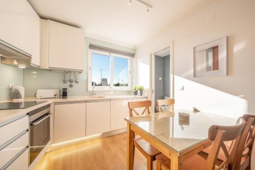 a kitchen with white cabinets and a table and chairs at GuestReady - Sunny spacious in Belém in Lisbon