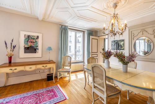 une salle à manger avec une table, des chaises et un lustre dans l'établissement GuestReady - Séjour vintage dans le 8e arr., à Paris