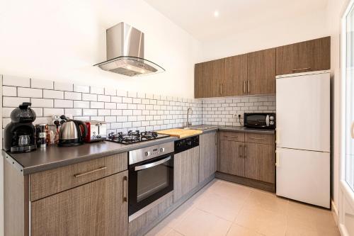 une cuisine avec des armoires en bois et un réfrigérateur blanc dans l'établissement La Belle-Hélène - Proche plage, 30 min d'ajaccio, à Albitreccia