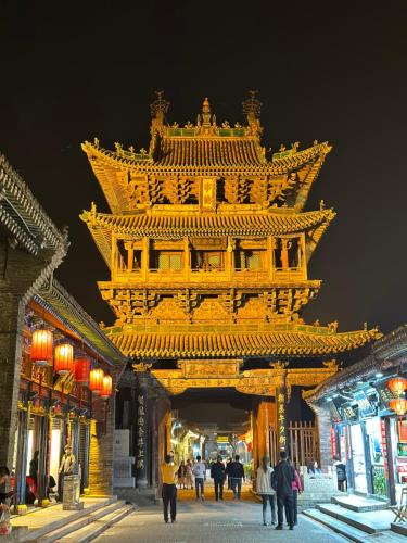 a large yellow building with people walking around it at Elsewhere Hotel Inn North Street Branch in Pingyao