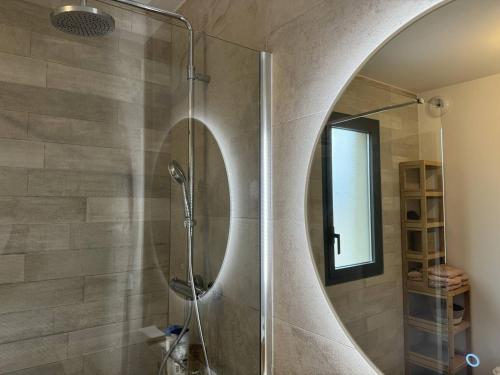 La salle de bains est pourvue d'une douche et d'un miroir rond. dans l'établissement Appartement tout confort vue mer, à Propriano