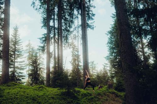 a person standing in a forest with a dog at Holzhotel Forsthofalm in Leogang