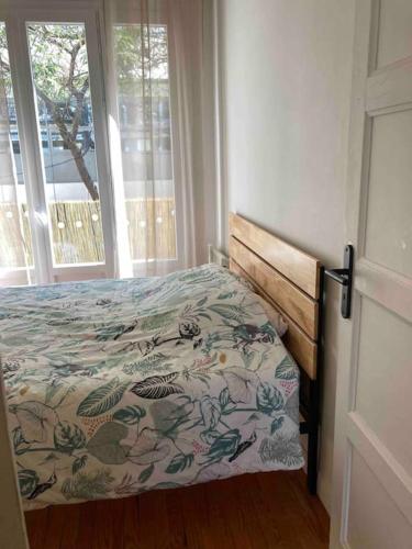 - une chambre avec un lit doté d'un couvre-lit floral et d'une fenêtre dans l'établissement Coeur de ville, balcon & parking gratuit, à Saint-Nazaire