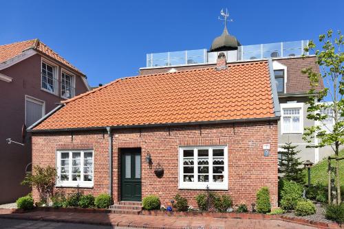 ein rotes Backsteinhaus mit orangefarbenem Dach in der Unterkunft Ferienwohnungen im Haus Hafenjuwel in Neuharlingersiel in Neuharlingersiel