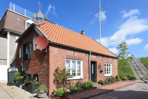 ein Backsteinhaus mit rotem Dach auf einer Straße in der Unterkunft Ferienwohnungen im Haus Hafenjuwel in Neuharlingersiel in Neuharlingersiel