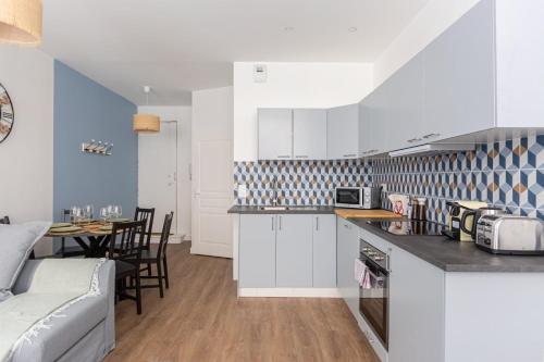 une cuisine avec des armoires blanches et une table avec des chaises dans l'établissement GuestReady - Flat in the city centre, à Bordeaux