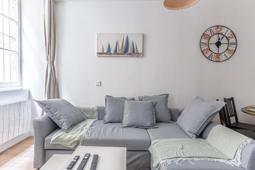 un salon avec un canapé et une horloge au mur dans l'établissement GuestReady - Flat in the city centre, à Bordeaux
