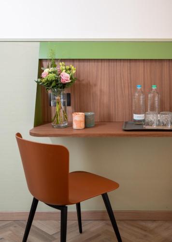 a chair and flowers on a wooden shelf at Hotel Casa Del Pellegrino in Padova