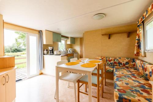 une cuisine avec une table et des chaises dans une pièce dans l'établissement L'héberge du lac d'Isachris mh4, à Queyrac