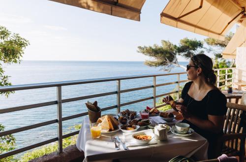 a woman sitting at a table with food and the ocean at Alivi in Bastia