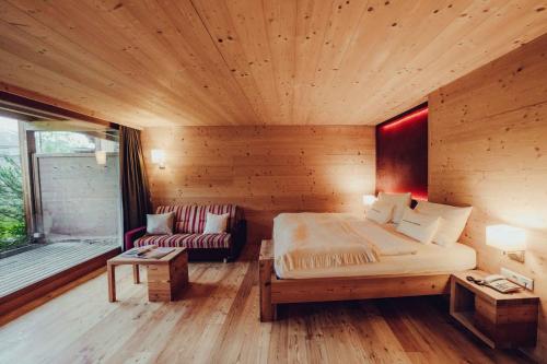 a wooden room with a bed and a couch at Holzhotel Forsthofalm in Leogang