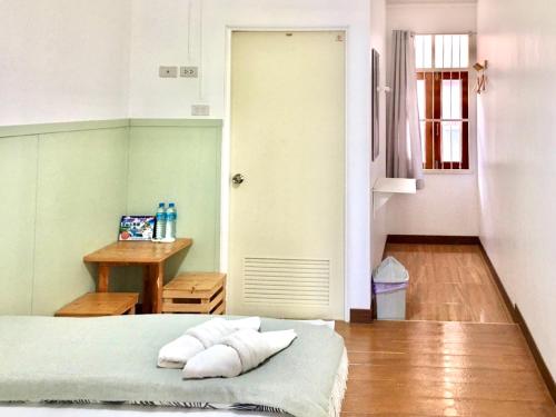 a bedroom with a bed and a table and a door at Thirty Tree Garden House in Chumphon