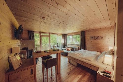 a bedroom with a bed and a desk in a room at Holzhotel Forsthofalm in Leogang
