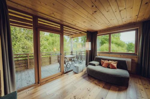 a living room with a couch and some windows at Holzhotel Forsthofalm in Leogang