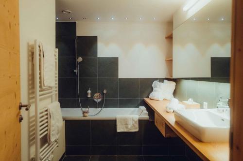 a bathroom with a sink and a bath tub at Holzhotel Forsthofalm in Leogang