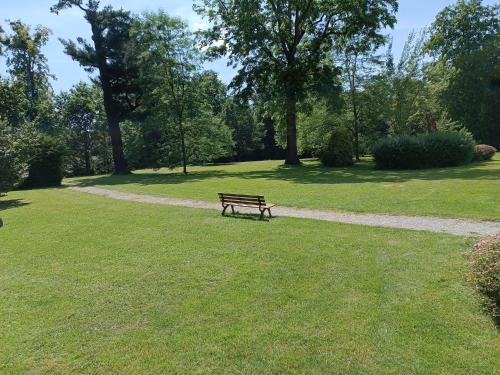 a park bench sitting in the grass near a path at Penzion na zámku Bartošovice in Nový Jičín