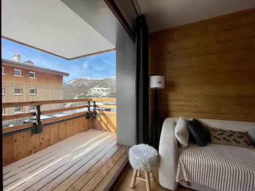 einen Balkon mit einem Bett und einem großen Fenster in der Unterkunft Homency - Résidence Fermes de l'Alpe C101 in L'Alpe-d'Huez