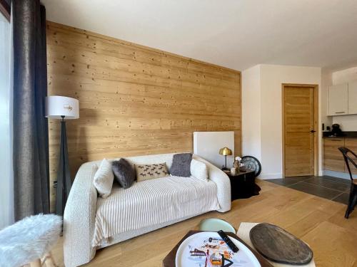 ein Wohnzimmer mit einem weißen Sofa und einer Holzwand in der Unterkunft Homency - Résidence Fermes de l'Alpe C101 in L'Alpe-d'Huez