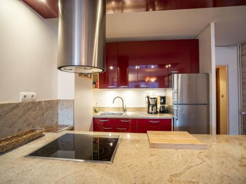 La cuisine est équipée de placards rouges et d'un réfrigérateur en acier inoxydable. dans l'établissement Appartement cosy avec balcon, Châtel - 6 pers., proche télésiège et centre, garage inclus - FR-1-676-172, à Châtel