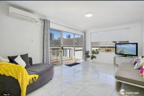 a living room with a couch and a flat screen tv at Stylish & Modern 2 bedroom Escape in Gold Coast
