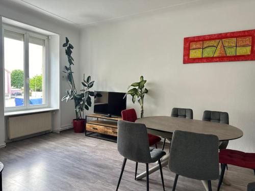 un salon avec une table, des chaises et une télévision dans l'établissement #Aujé - Appart Mulhouse Centre, à Mulhouse