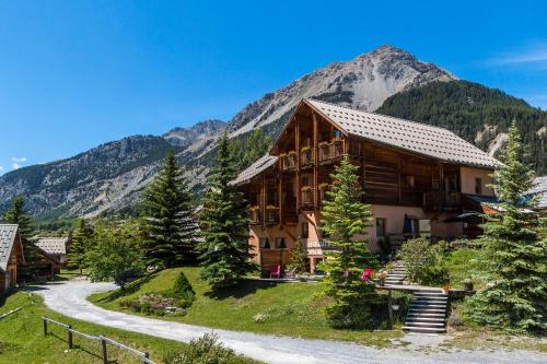 a log cabin in the mountains with a winding road at Le Chalet d'en Hô in Névache