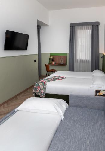 a room with three beds and a flat screen tv at Hotel Casa Del Pellegrino in Padova