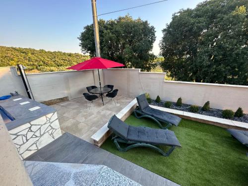 a patio with a table and two chairs and an umbrella at MM Villa, Strandnahe Villa mit Pool & Whirlpool in Kruševo in Kruševo