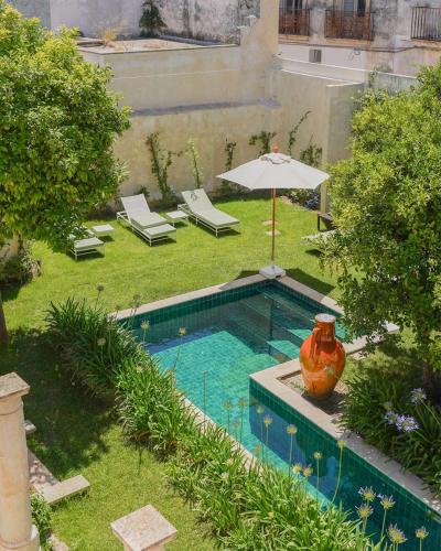 a swimming pool with an umbrella and a vase in a yard at Palazzo Muci in Nardò