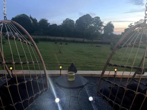 a patio with two swings and a table and a field at Spacious Luxury countryside retreat in Estry