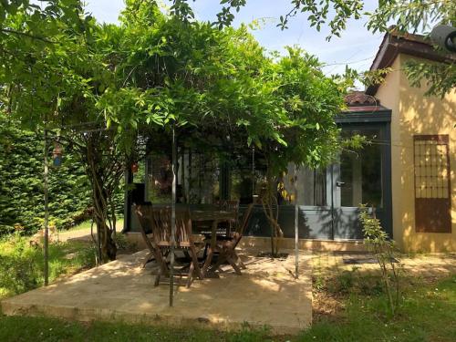 une table et des chaises sous un arbre dans une cour dans l'établissement Des Châteaux entre les Feuilles - Parc vue Village, à Puy-lʼÉvêque
