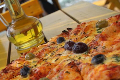 a pizza with olives on top of a table at FKK Ada Bojana in Ulcinj