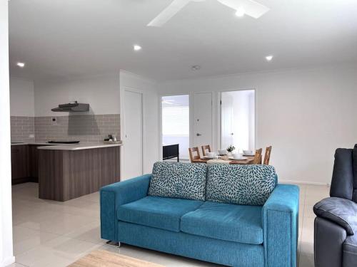 a blue couch in a living room with a table at 2 Bedroom Self-Contained Accommodation with Aircon in Bellbird Park