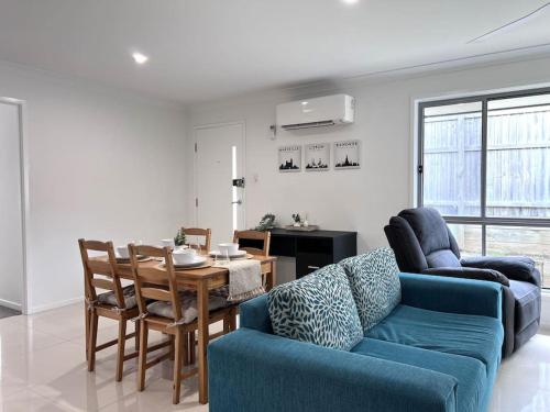 a living room with a blue couch and a table at 2 Bedroom Self-Contained Accommodation with Aircon in Bellbird Park