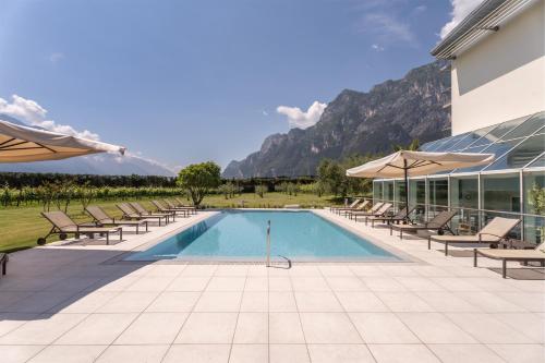 a swimming pool with chairs and umbrellas next to a building at Hotel Al Maso in Riva del Garda