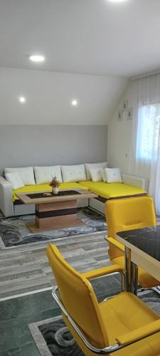 a room with yellow beds and tables and chairs at Apartmani Romansa Perucac in Perućac