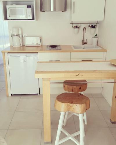 une cuisine avec une table en bois et un tabouret dans l'établissement Oyat gîte écologique à Porspoder, à Porspoder