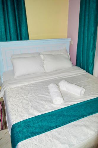 a bed with white sheets and pillows and green curtains at Angie's staycation 1br apt Milimani- Fast internet, secure parking, Free netflix in Kisumu