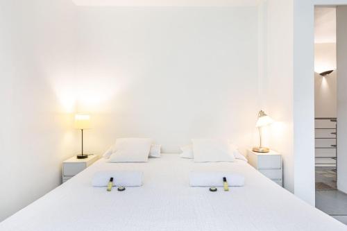 - une chambre blanche avec 3 lits et 2 lampes dans l'établissement GuestReady - Charming haven with a private garden, à Nogent-sur-Marne