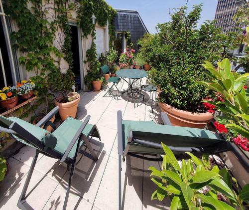 un patio avec des tables, des chaises et des plantes en pot dans l'établissement GuestReady- 2 Terrace Duplex with Exceptional View, à Paris