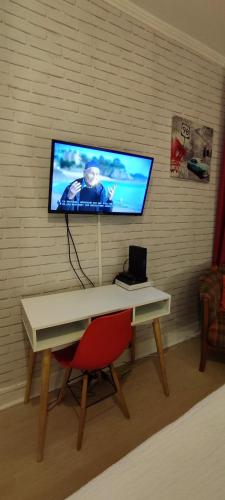 a television on a wall with a desk and a chair at Cosy-2 pers-Coeur de ville-Proche Bd Pyrénées in Pau