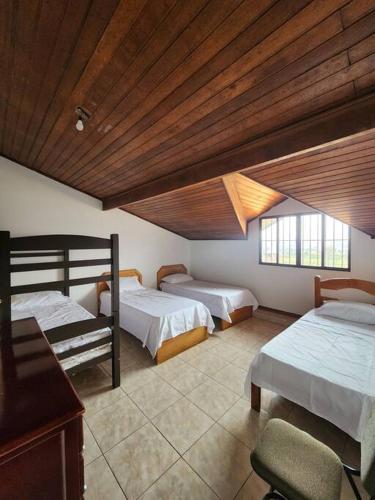a bedroom with two beds and a wooden ceiling at Casa grande com piscina Chácara do Dinho in Londrina