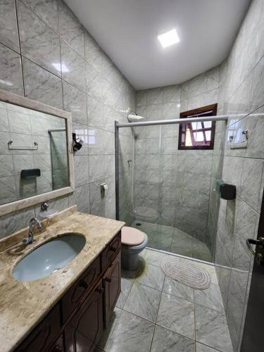 a bathroom with a shower and a sink and a toilet at Casa grande com piscina Chácara do Dinho in Londrina