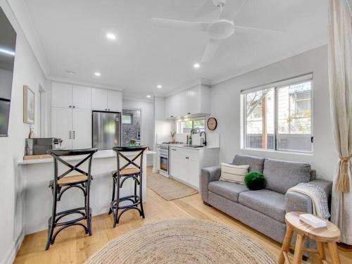 a living room with a couch and a kitchen at Comfort Cove - quiet luxury with full kitchen in Brisbane