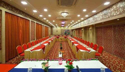 a long banquet hall with red chairs and tables at Royal Court in Madurai