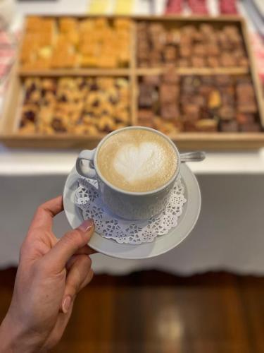 una persona sosteniendo una taza de café en un plato en Kenton Palace Buenos Aires, en Buenos Aires